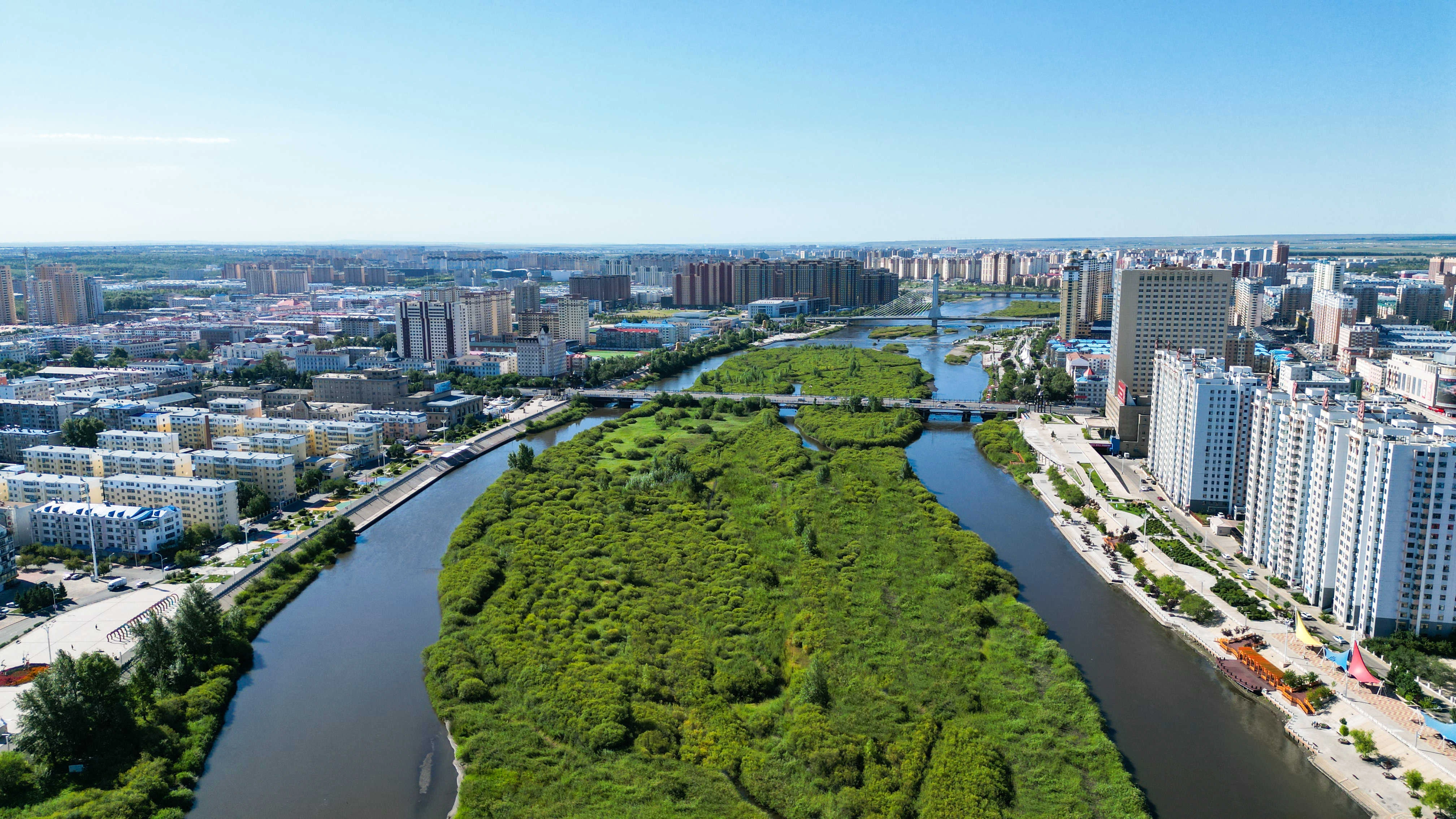 Vast Hulunbuir grassland with winding river and grazing livestock under blue sky