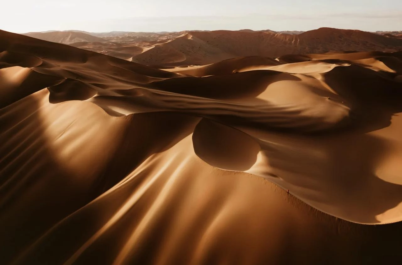 Golden sand dunes of Badain Jaran Desert under dramatic sunset sky