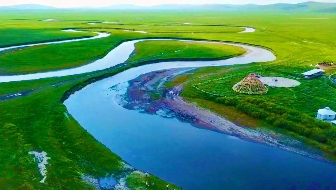 Panoramic view of Hulunbuir Grassland with winding Morin Gol River and grazing horses