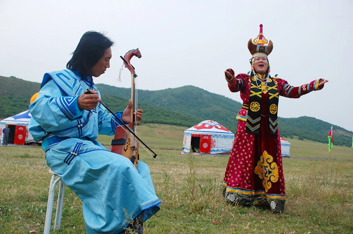 Mongolian singer performing traditional long song on grassland with horse-head fiddle accompaniment