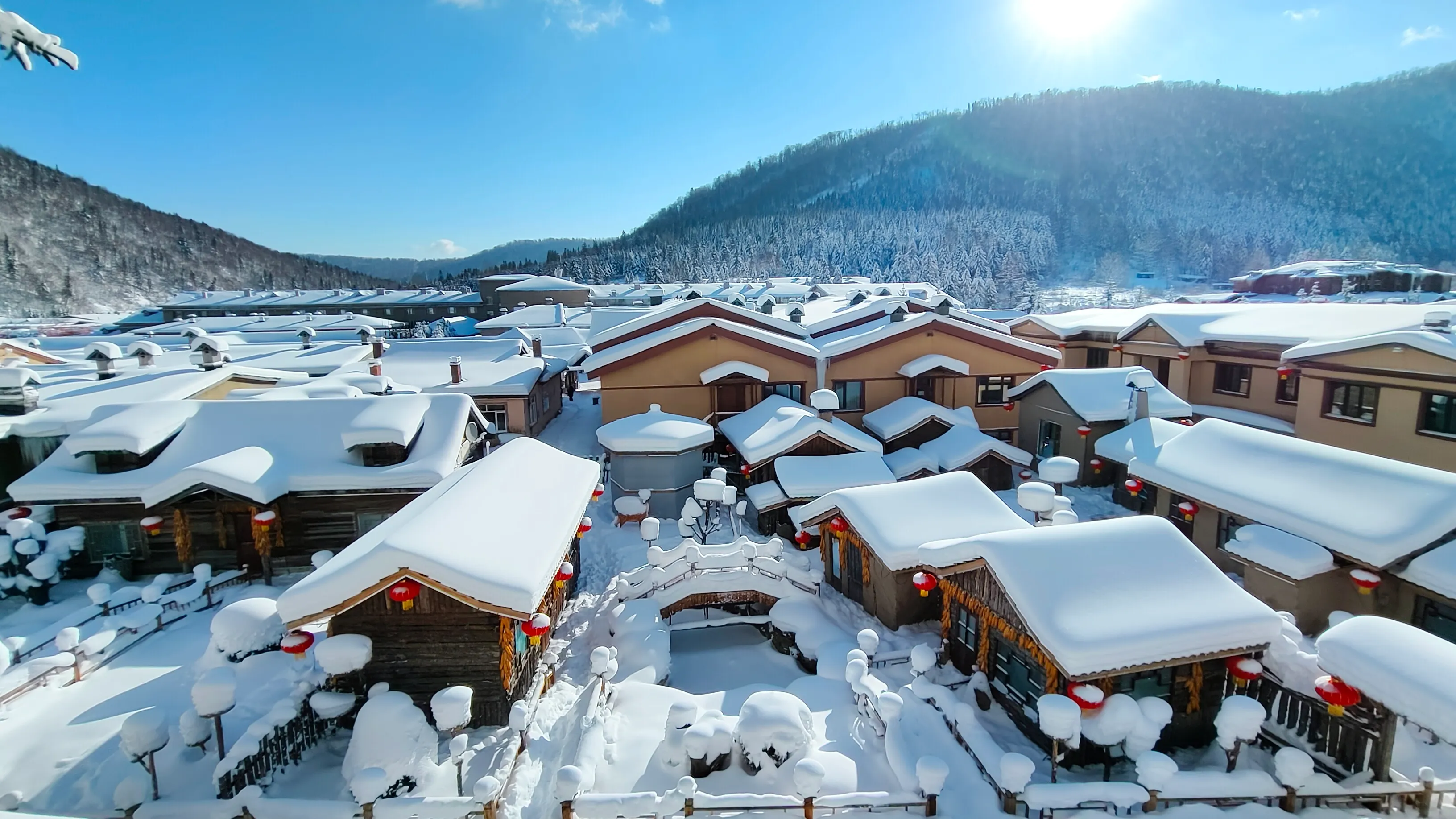 Snow-covered wooden houses with red lanterns in Xuexiang Snow Town