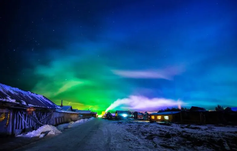 Mohe Beiji Village under northern lights with snowy landscape and traditional buildings