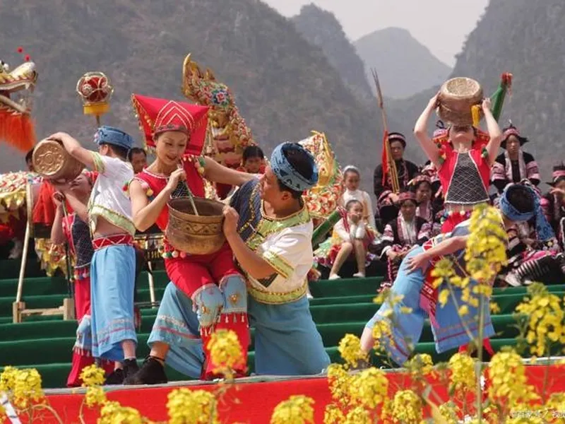 Zhuang villagers singing and dancing during the March 3rd Festival amid misty mountains, colorful ribbons fluttering