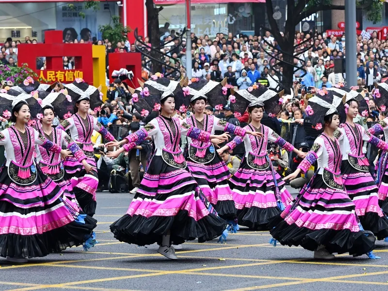 Miao women in colorful ceremonial dress with silver headpieces dancing and playing lusheng instruments in the mountains