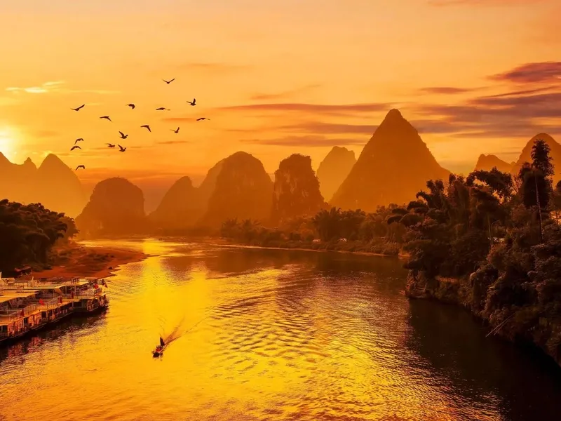 Li River winding through karst peaks from Yangdi to Xingping, boats gliding on mirrored waters, misty mountains resembling a Chinese ink painting