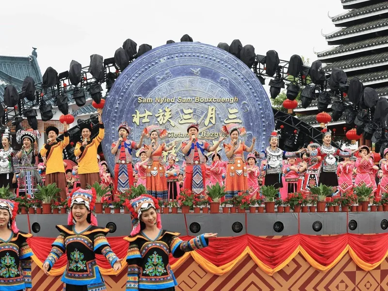 Zhuang youths performing antiphonal singing during the March 3rd Festival, colorful ribbons fluttering in the mountains