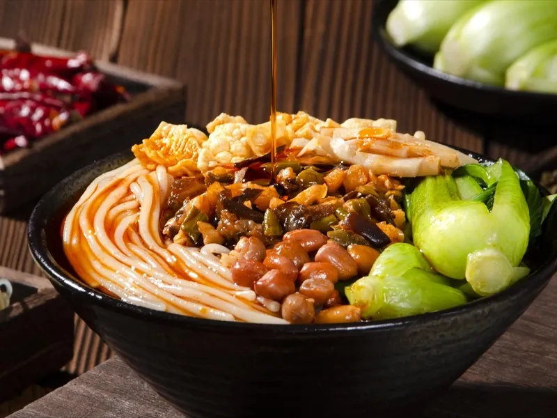 Liuzhou river snail rice noodles served with pickled bamboo shoots, peanuts, and tofu skin