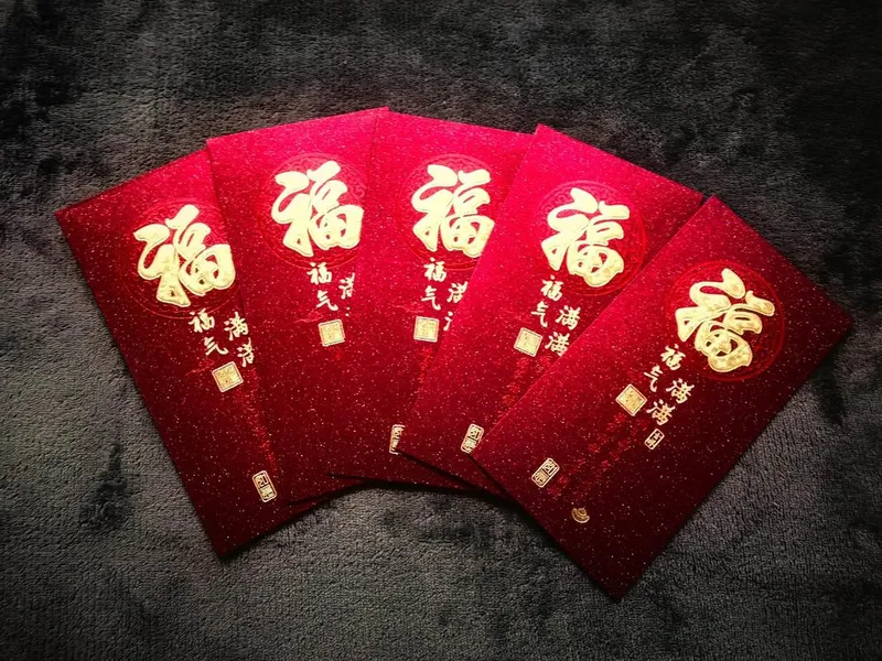 Traditional Chinese red envelopes with gold patterns and new banknotes