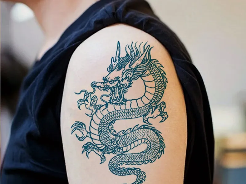 Modern Chinese dragon tattoo on an arm, featuring flowing scales and clouds
