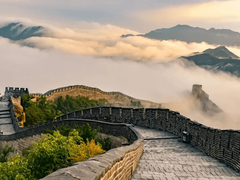 A panoramic view of the Great Wall of China winding over mountain ridges at dawn