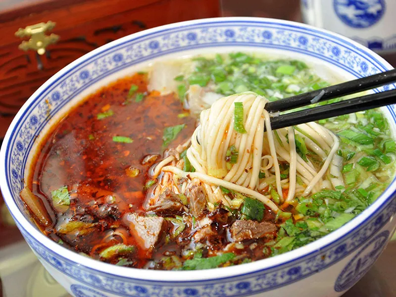 Bowl of Lanzhou beef noodles with hand-pulled noodles and chili oil
