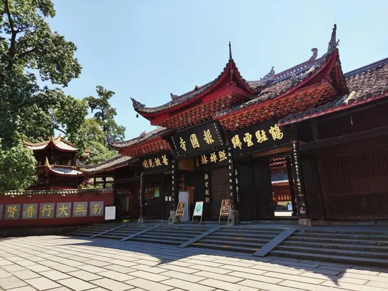 Cable car ascending steep cliffs toward Mount Emei's higher temples and snow-capped peaks in the distance.
