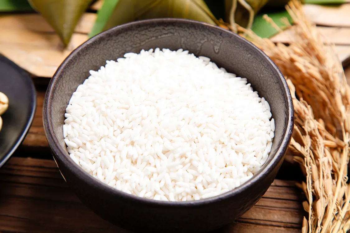 Close-up of perfectly cooked sticky rice (glutinous rice) in a bamboo steamer, showcasing its chewy texture, ideal for both savory dishes like zongzi and sweet desserts like mango sticky rice in Asian cuisine.