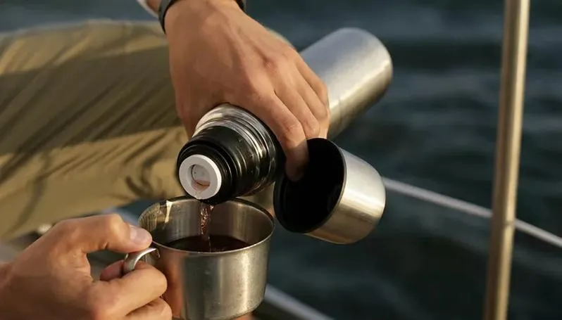 A stainless steel insulated cup filled with hot water and herbal ingredients like wolfberries and chrysanthemum, representing China’s thermos culture and the everyday ritual of carrying warmth throughout the day.