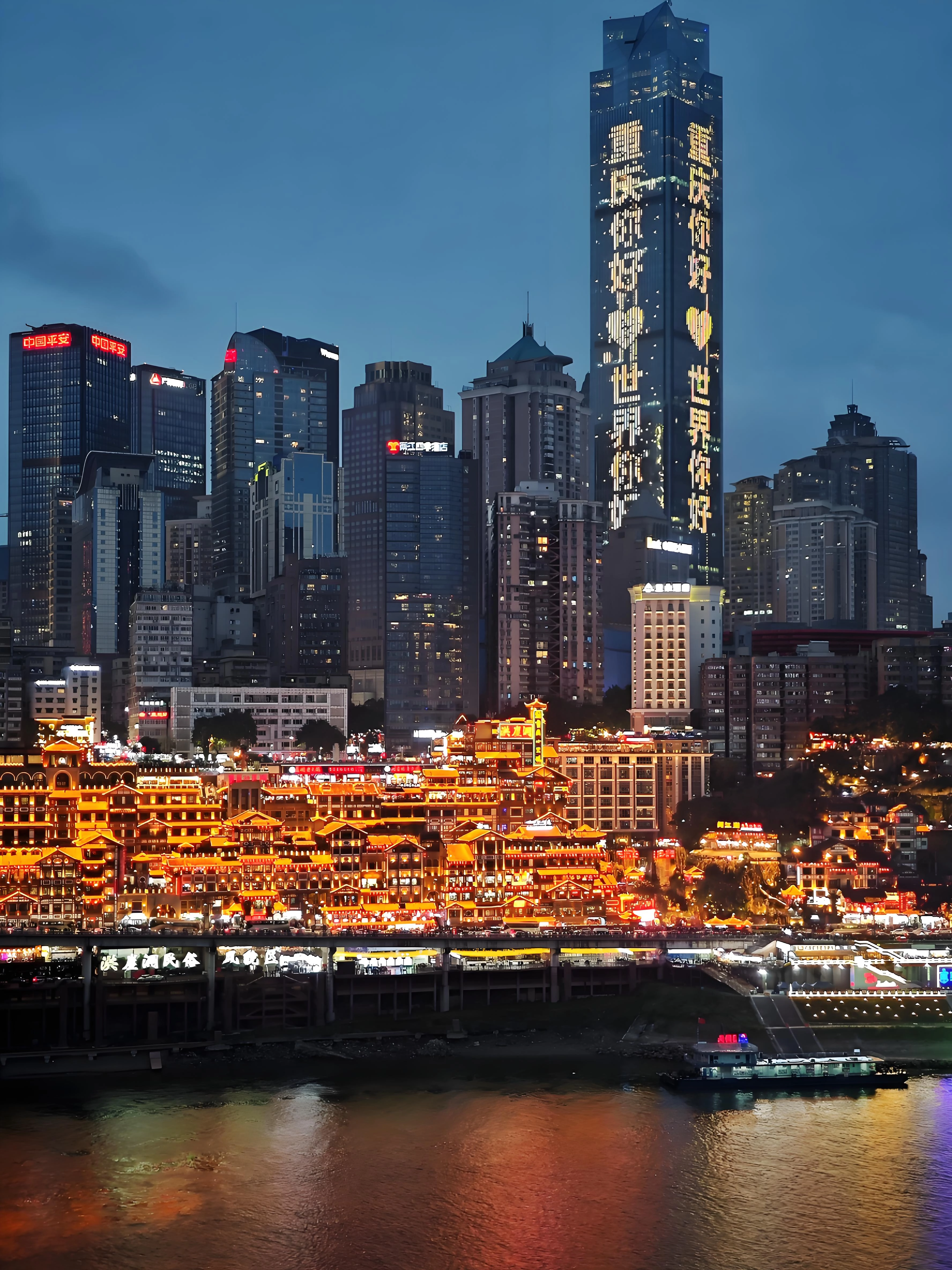 Night view of Hongya Cave in Chongqing, showing stilted riverside buildings illuminated against the hillside, reflecting traditional Bayu architecture and vibrant local culture.